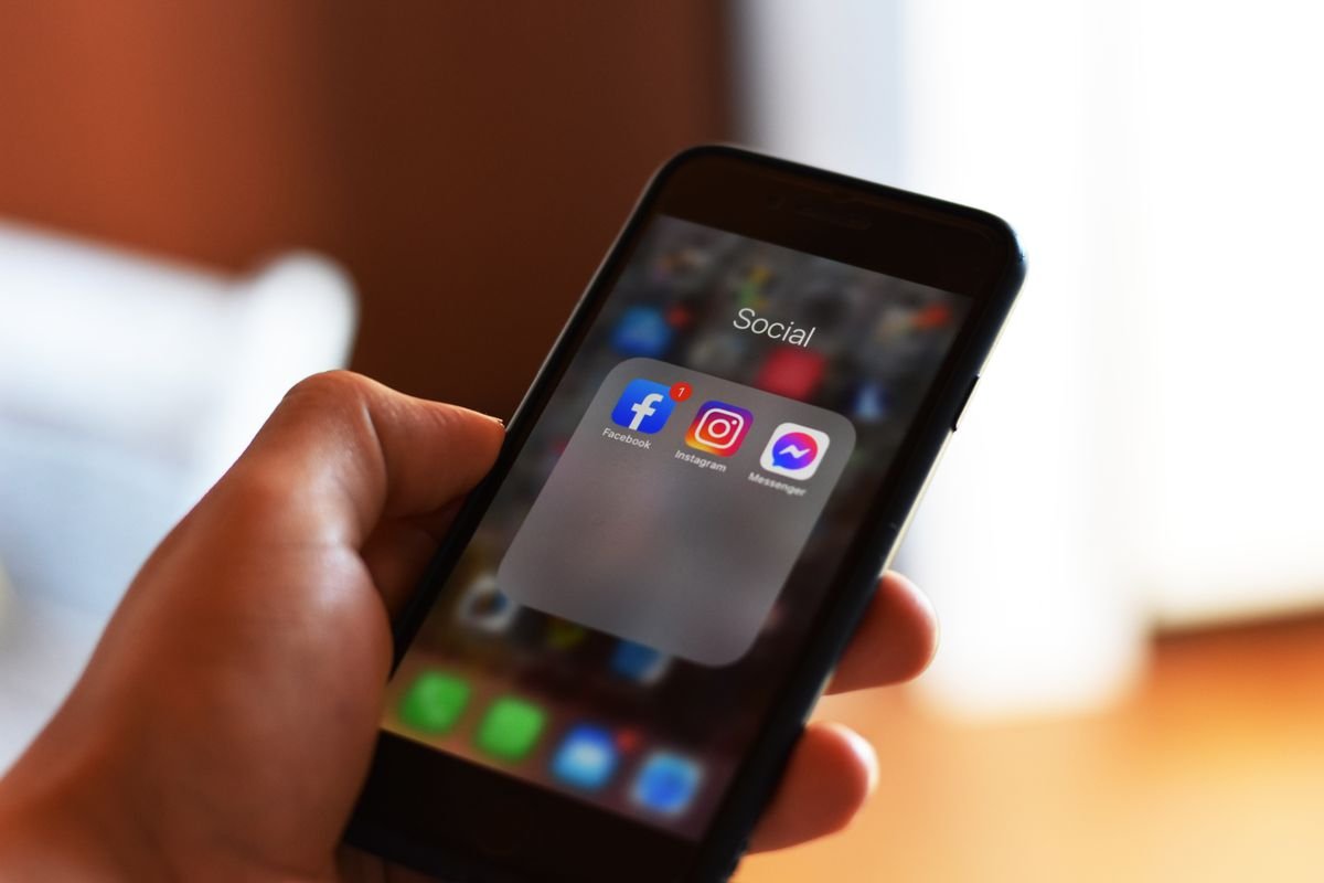 Hand holding a smartphone showing social media app icons